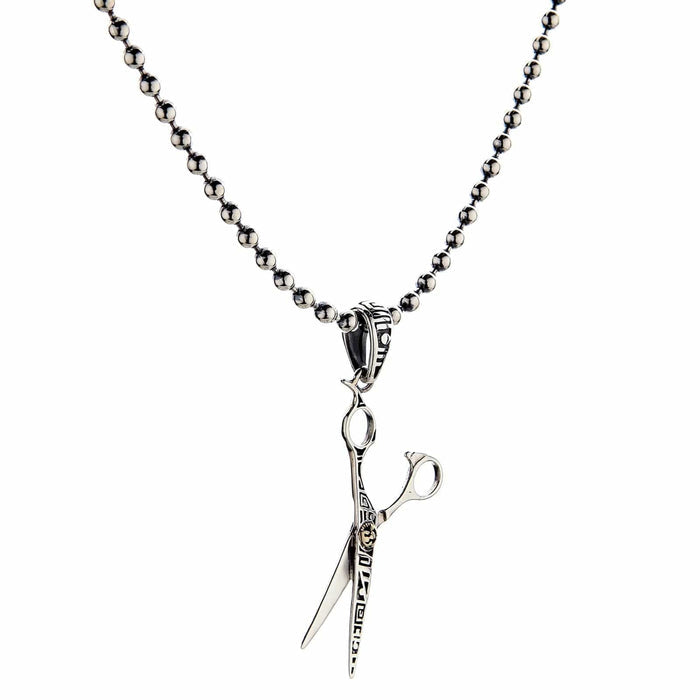 An angled view of the unique sterling silver scissors pendant, showing its polished finish.