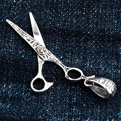 A macro shot of the ornate, handcrafted silver bail on the scissors pendant.