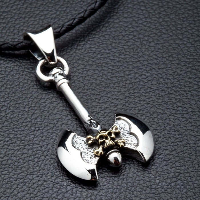 A sterling silver Viking axe pendant with a brass skull detail shown on its complimentary black leather cord.
