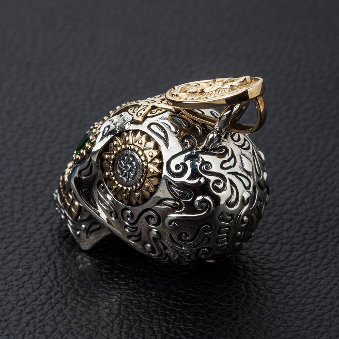Gold gear-flower disc fills one eye socket while a green stone sits on the brow above deep scrollwork.