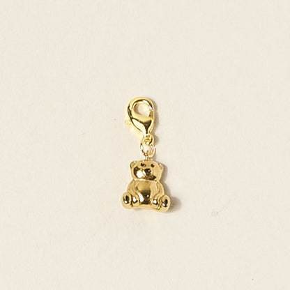 The Darling Effect's Teddy Bear Jewelry Charm Gold is a small, shiny gold charm with a lobster clasp, perfect for your favorite charm bar. Shown on a plain off-white background.