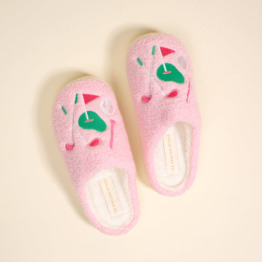 The Golf Edit Fuzzy Slippers by The Darling Effect feature pink fuzz, embroidered golf-themed patches in pink and green, and a plush white sherpa lining for the coziest comfort on or off the course.