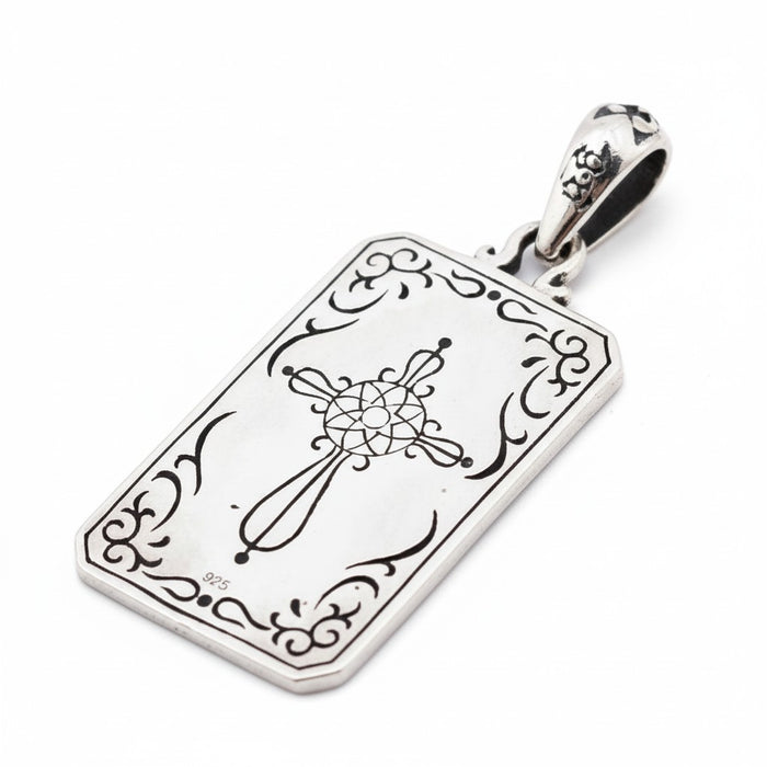 The back of The Magician tarot pendant, showing a detailed, engraved cross design.
