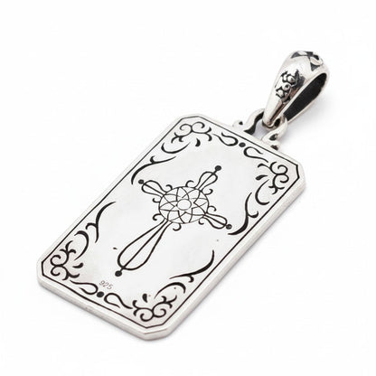 The back of The Magician tarot pendant, showing a detailed, engraved cross design.