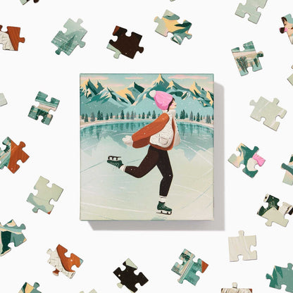The Skater | 100 Piece Jigsaw Puzzle by Ordinary Habit features a hand-drawn scene of ice skating on a frozen lake with mountain backdrops—an ideal pick for anyone who enjoys charming winter puzzles.