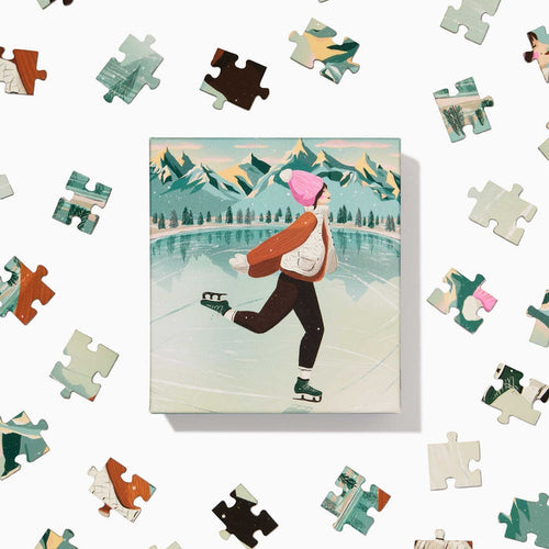 The Skater | 100 Piece Jigsaw Puzzle by Ordinary Habit features a hand-drawn scene of ice skating on a frozen lake with mountain backdrops—an ideal pick for anyone who enjoys charming winter puzzles.