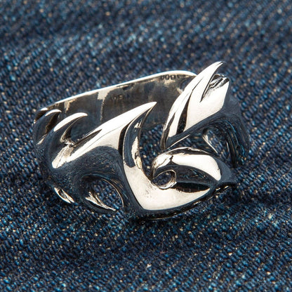 A men's gothic tribal ring resting on a denim background, highlighting its sharp design.