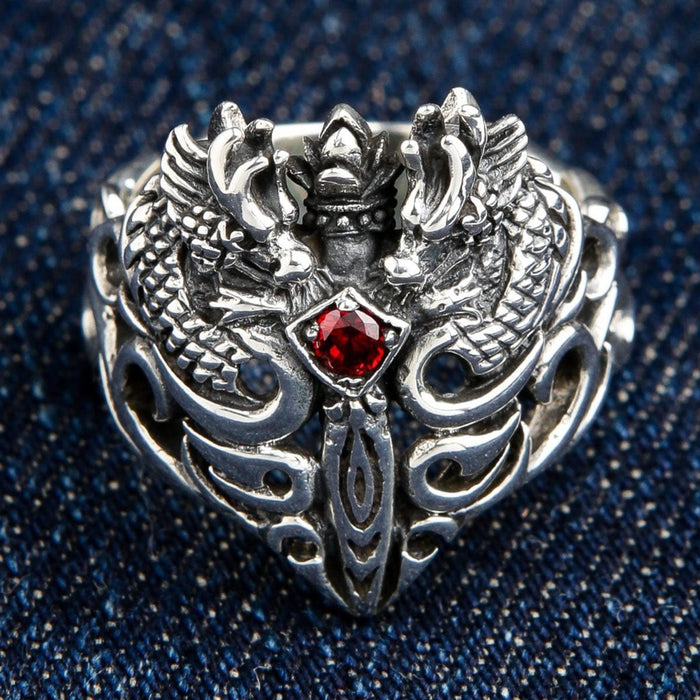 Front view of 925 sterling silver twin dragon ring with red garnet centerpiece on denim background