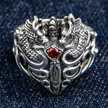 Front view of 925 sterling silver twin dragon ring with red garnet centerpiece on denim background