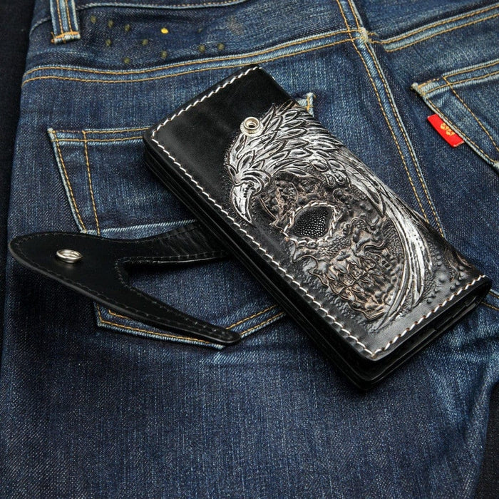 Winged skull wallet with snap closure open showing carved leather eagle feather details and stingray face inlay