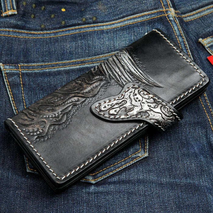 Handmade biker wallet back view featuring carved dragon design and decorative snap closure on denim